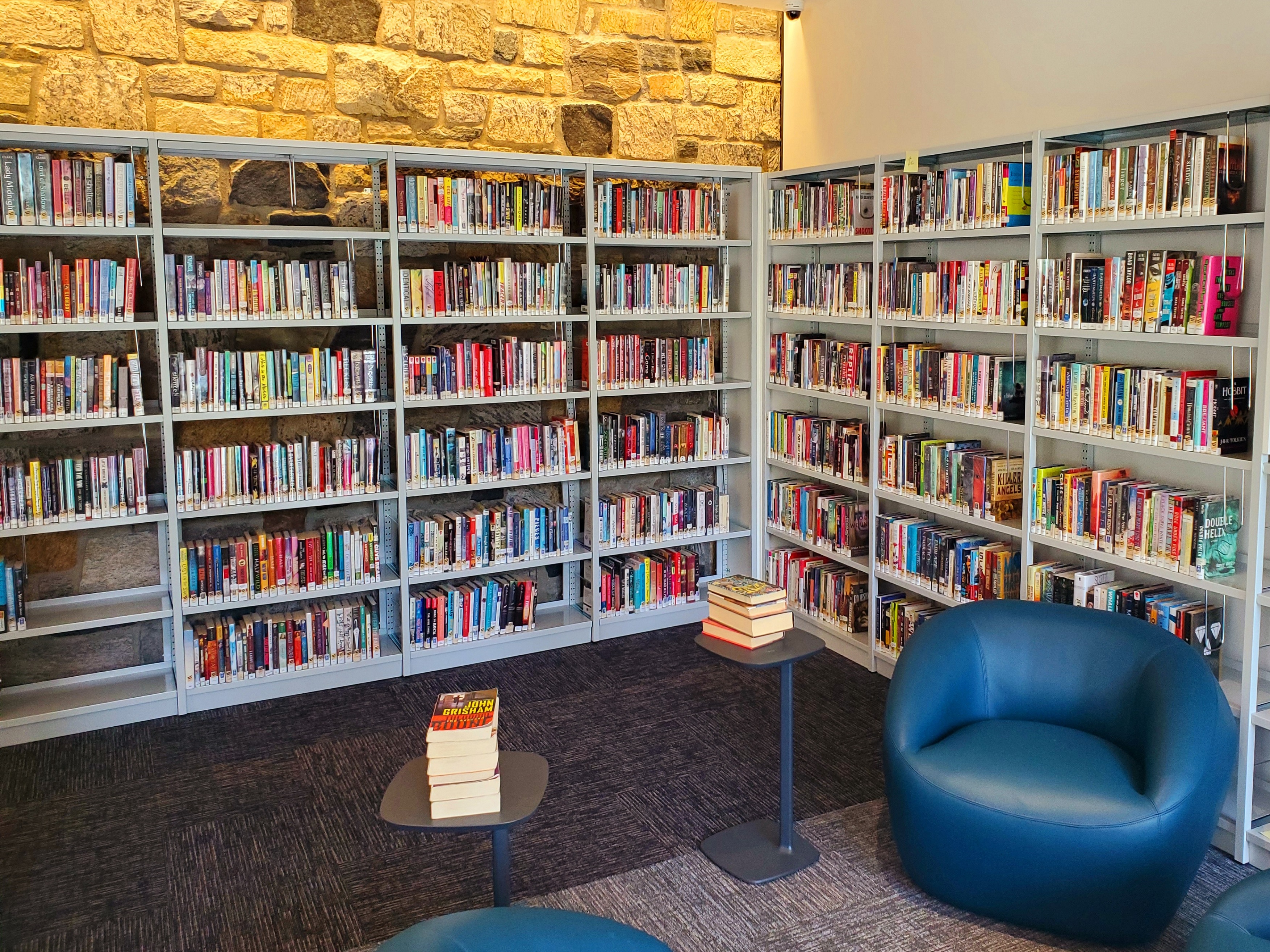 Teen Space interior photo showing a blue lounge chair and stacks of teen books