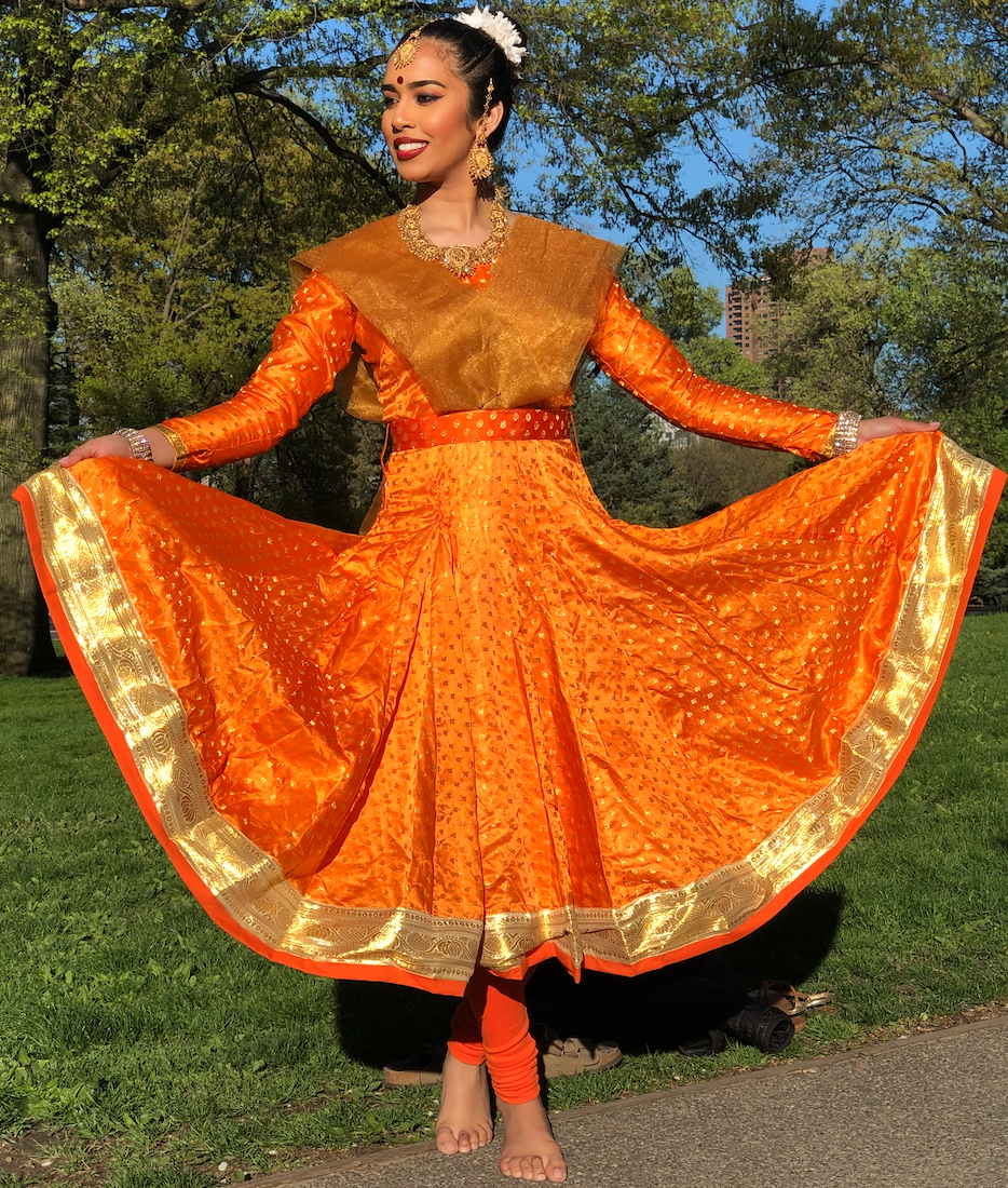 Kathak dancer in bright orange dress with gold trim