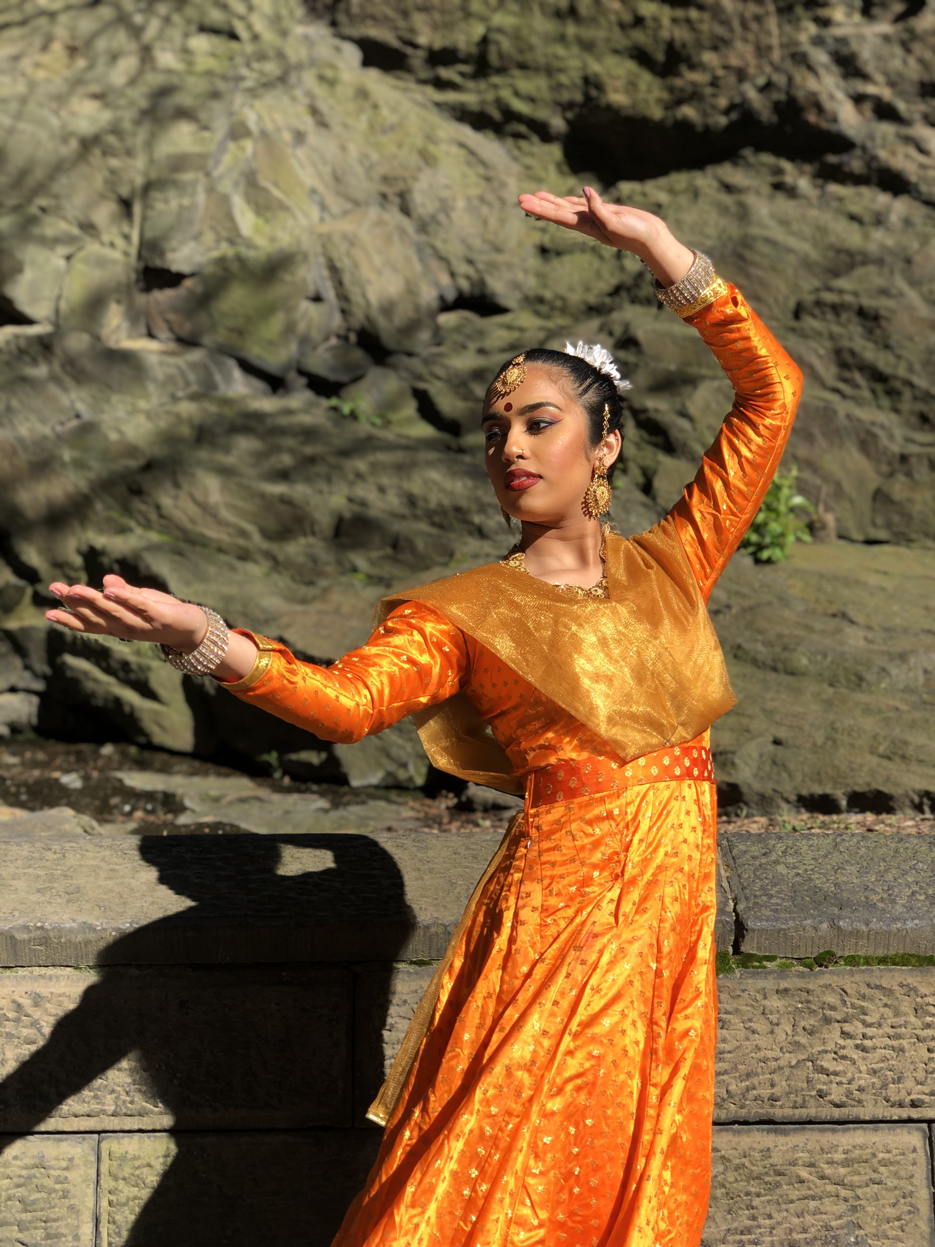Kathak dancer in marigold-orange dress with gold trim