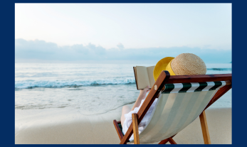 person in a sun hat lying on a sling chair reading a book with the sand and ocean waves in front of them