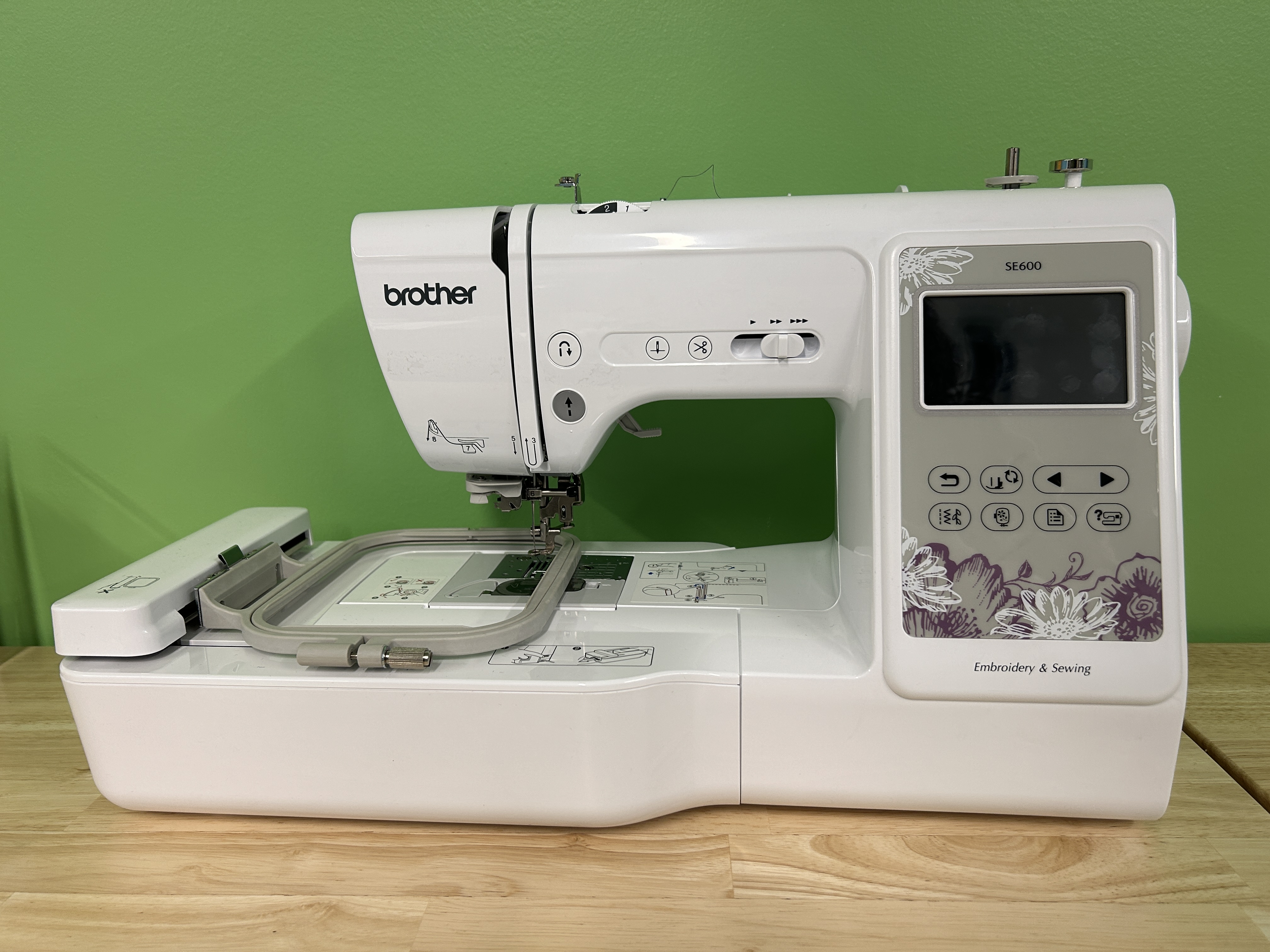 A picture of a Brother SE600 embroidery machine against a green wall