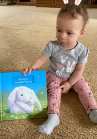 Baby girl holding "Aurelia's Snuggle Bunny" storybook